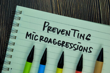 Wall Mural - Preventing Microaggressions write on a book isolated on Wooden Table.