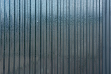 Wall of hangar from corrugated metal sheet of gray color.