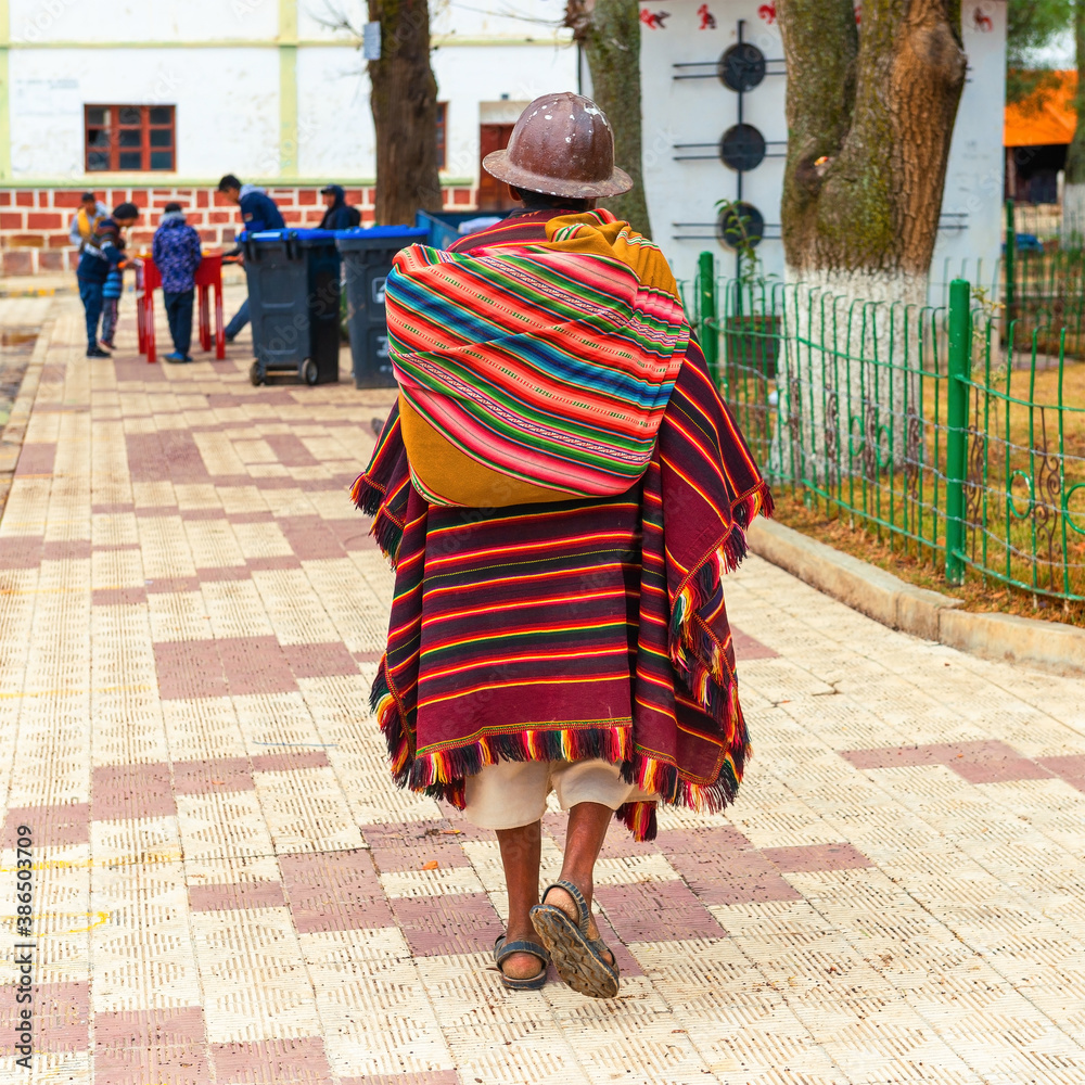 Photo Stock Senior Bolivian indigenous Tarabuco man in traditional clothing  (poncho and hat) walking on the main square, Tarabuco, Bolivia. | Adobe  Stock