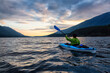 Beautiful View of Person Kayaking on Scenic Lake at Sunset surrounded by Mountains in Canadian Nature. Taken in Golden Ears Provincial Park, near Vancouver, British Columbia, Canada.