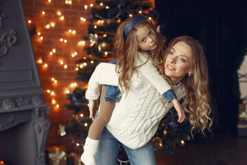 Beautiful mother in a white sweater. Family with cristmas gifts. Little girl near christmas tree