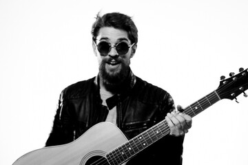 A man holds a guitar in his hands music emotions black leather jacket dark glasses studio light background