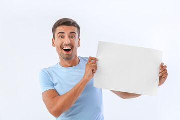 Young man with blank paper sheet on white background