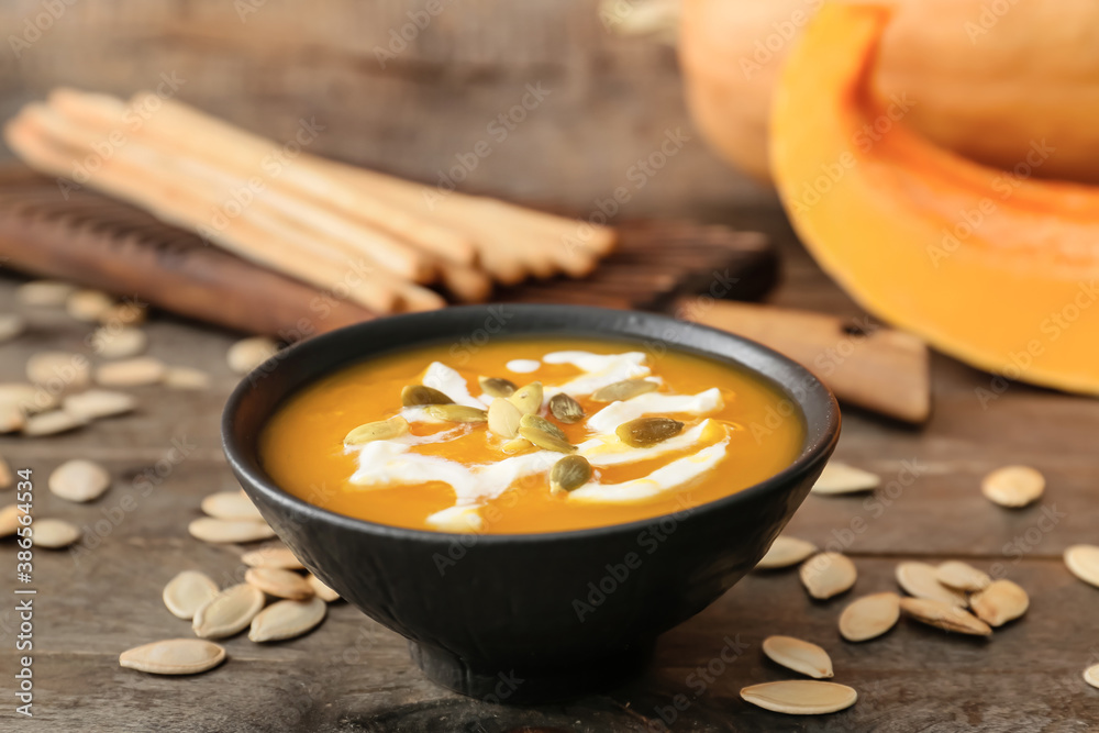 Tasty pumpkin cream soup in bowl on table