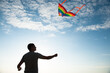 © ruslanshug - young active male with flying multicolored kite on sea and blue sunset sky background