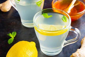 Wall Mural - Ginger tea with lemon on a dark background. Two cups of ginger tea and ingredients for its preparation