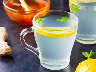 Wall Mural - Ginger tea with lemon on a dark background. Two cups of ginger tea and ingredients for its preparation