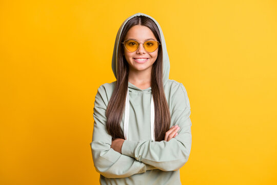 portrait of cheerful school girl folded arms wear sunglass light green clothing isolated on yellow c