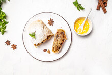 Classic apple strudel with filo pastry filled with sliced caramelized apples, cinnamon star anise, served on a light background, top view, copy space