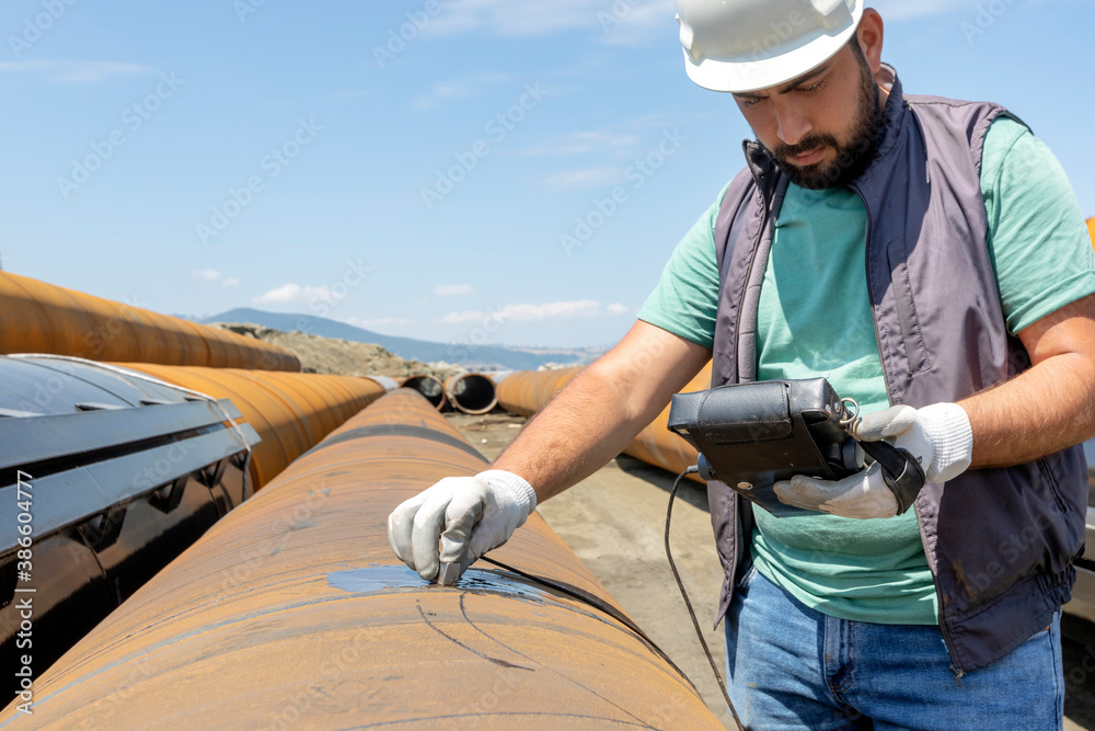 Non-destructive testing technician is checking welds of pipe with ...