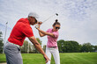 Experienced tutor instructing a female golf player