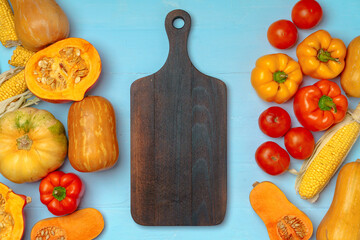 Autumn background with fresh vegetables and wooden cutting board