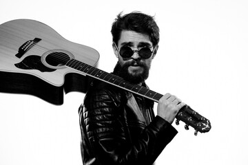 A man holds a guitar in his hands music emotions black leather jacket dark glasses studio light background