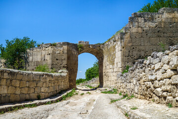 Wall Mural - City gates inside cave fortress Chufut Kale, Bakhchisaray, Crimea. Bricks on both side of street are remains of middle fortification walls