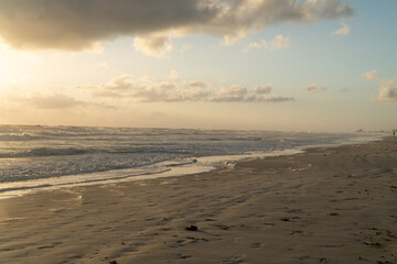 Beautiful Wilbur Beach Florida at sunrise with golden light reflecting off the clouds water and sand