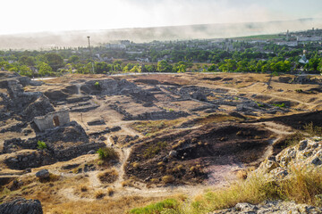 Wall Mural - Remains of antique city Panticapaeum & modern city Kerch (Crimea) on background. Smoke above city makes a very dramatic feeling