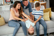 © JustLife - Young family enjoying at home. Mother and father tickling son.