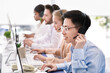 © Prostock-studio - Asian helpdesk representative in headphones with his colleagues providing tech support services to customers, copy space
