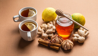 Natural cold and flu home remedies: hot tea cups with lemon, honey, ginger, cinnamon and garlic to boost immune system. Natural healthy food ingredients for immunity stimulation, viruses protection.