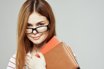 Female student with notepad and glasses on a light background cropped view of a striped T-shirt