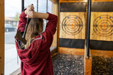 Fototapeta  - Young girl throws an axe at a target in an axe throwing range