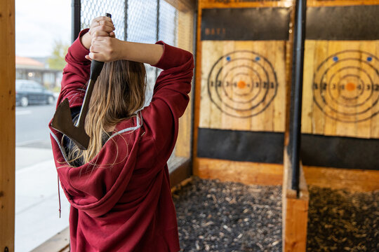 young girl throws an axe at a target in an axe throwing range