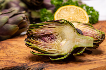 Fresh french petit violet artichokes heads cultivted in Brittany, France with lemon and parsley