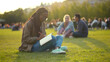 © TommyStockProject - Afro female student writing in exercise book and doing homework in summer park