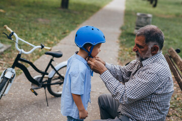 Wall Mural - grandfather with his grandson preparing for a ride with bike