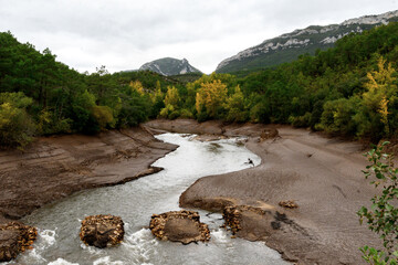 Wall Mural - Rio ebro a su paso por Burgos medio vacio con los lados llenos de barro, al fondo las montañas, y a los lados los arboles, ambiente de otoño temprano