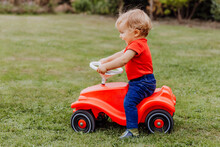 Baby Girl Riding Toy Car In Garden