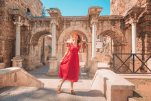 Happy Female Tourist Traveler Discover Interesting Places And Popular Attractions And Walks In The Old City Of Antalya, Turkey. The Famous Roman Gate Of Hadrian