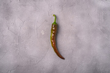 Wall Mural - Hot spicy green and red chili pepper on stone concrete background, top view copy space