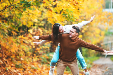 Wall Mural - Happy family walking in autumn park on sunny fall day