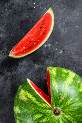 Wall Mural - Red ripe watermelon with cut-out slices. Black background. Top view