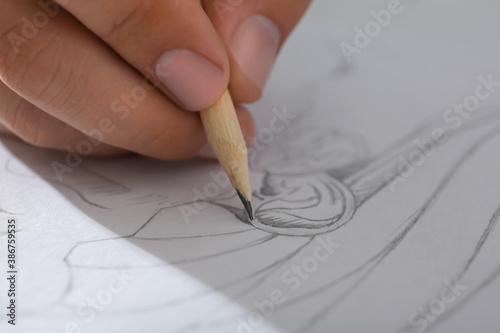 Man drawing portrait with pencil in notepad, closeup