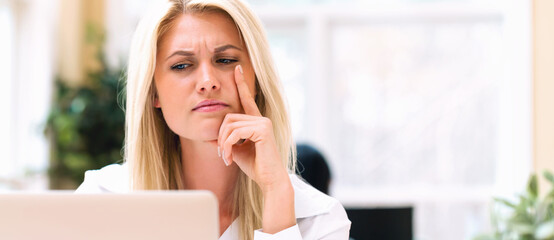 Wall Mural - Unhappy young woman sitting at her desk in front of the computer