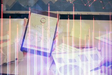 Double exposure of man's hands holding and using a digital device and forex graph drawing. Financial market concept.