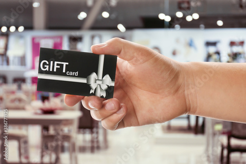 Man holding gift card in cafe, closeup
