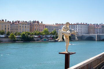 Wall Mural - Statue de style Antique sur les rives du fleuve Rhône avec le fleuve bleu, et la ville de Lyon à l'arrière plan, un jour ensoleillé, avec un ciel bleu sans nuage