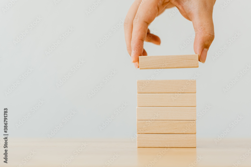 Hand arranging wood block stacking on top with wooden table. Business concept for growth success process - obrazy, fototapety, plakaty 