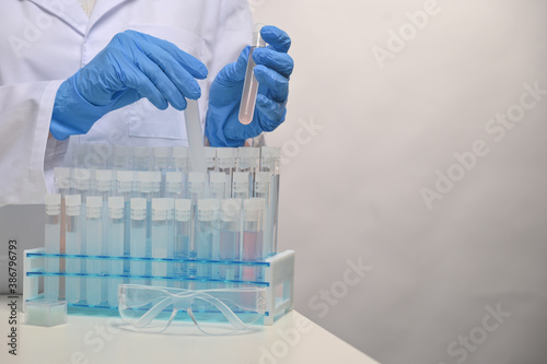 Close-up view of hands in protective blue gloves keeps biological tubes with samples covid-19 vaccine. Backstage of scientific discovery. Healthcare concept.