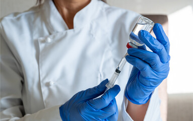 Doctor or scientist in laboratory holding  liquid vaccines bottle with syringe.