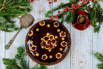 Wall Mural - Cherry chocolate cake with cup of coffee and pine branch with red berries.