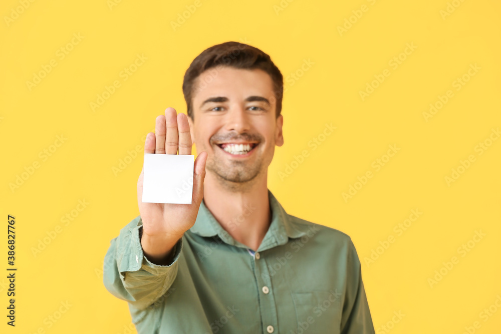 Young man with small blank paper sheet on color background