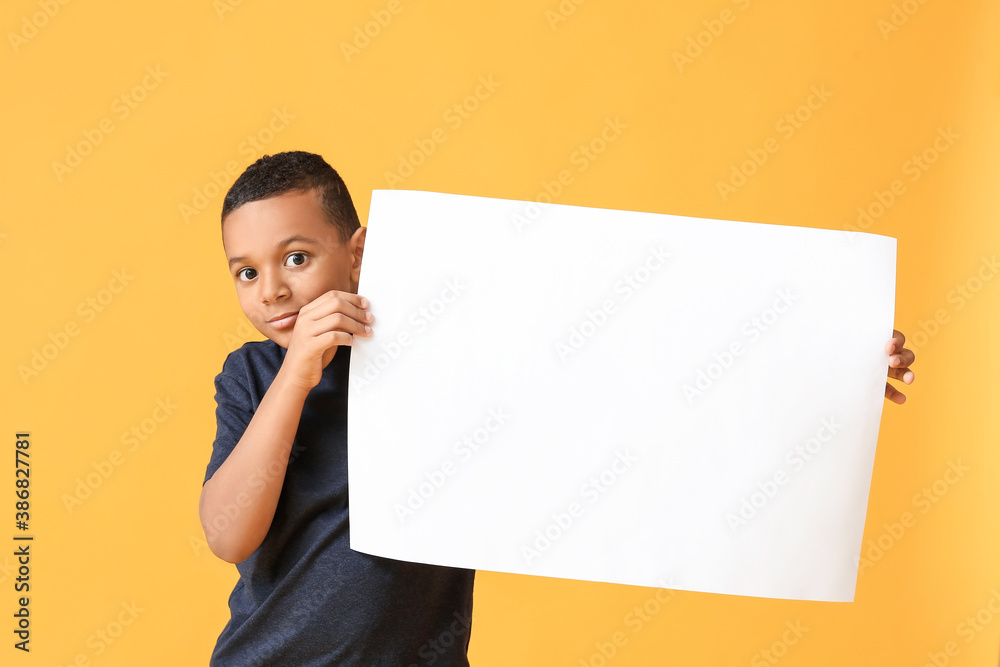 Little African-American boy with blank poster on color background