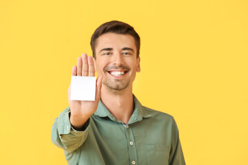 Wall Mural - Young man with small blank paper sheet on color background