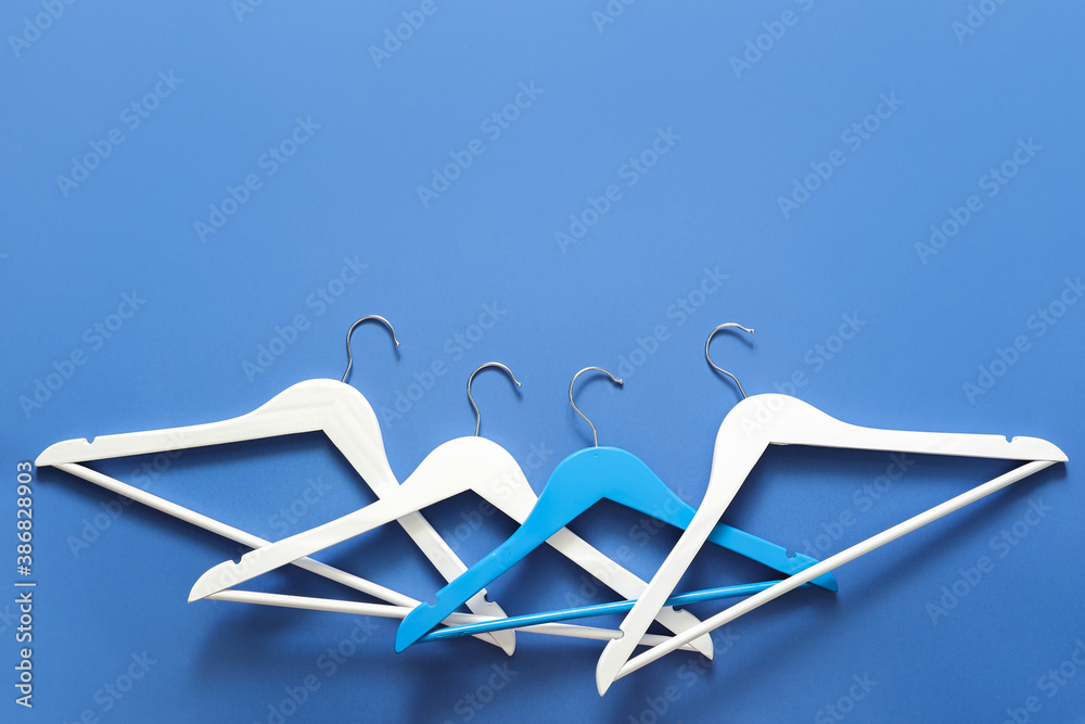 Clothes hangers on color background