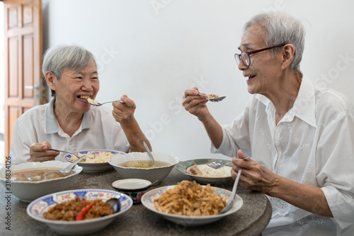 Happy smiling asian senior women eating Thai food,sitting at dining table in the house,old people talking and enjoy during breakfast,eat with rice,local cuisine,health care,healthy food of elderly