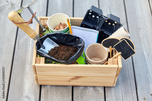gardening, farming and planting concept - garden tools in wooden box and soil and pots